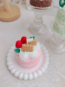 Close-up of pink layered cake scented candle with cream flower and red berries