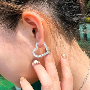 Orecchini a cuore in argento con zirconi indossati da una modella alla luce esterna