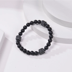 Close-up of black matte and grey volcanic stone beaded bracelet on geometric stands
