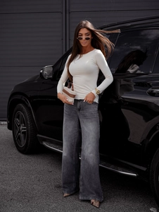 Chic urban street style detail showing cream slim-fit knit top and high-waist wide jeans
