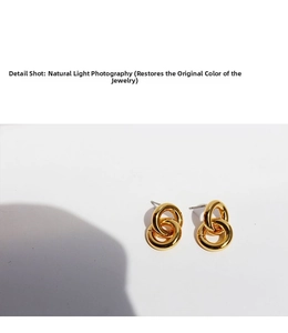 Detail shot of interlocked golden double circle earrings with polished metallic finish