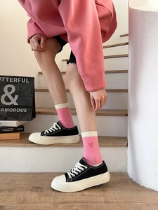 Detail of pink striped socks featuring heart embroidery styled with platform sneakers