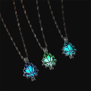 Luminous lotus pendant necklaces glowing in blue and green on a dark background