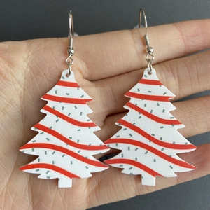 Hand holding festive Christmas tree earrings with colorful wavy pattern and green dots
