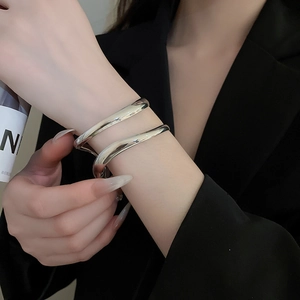 Macro shot of a double-layered silver metallic crossover cuff bracelet on a model's wrist