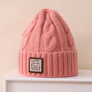 Close-up of pink cable knit beanie featuring a cute bear leather patch and Lucky text