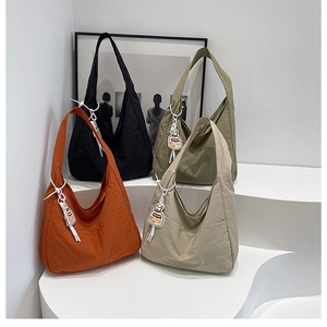 Selection of wrinkled nylon tote bags in orange, black, green and beige on white steps