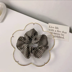 Detailed view of a black and white houndstooth scrunchie in a decorative glass tray