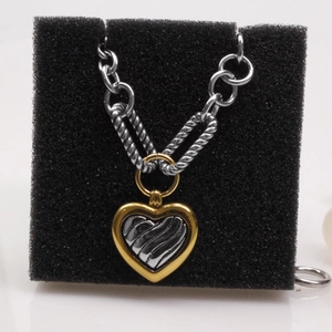 Detail of a two-tone heart pendant featuring gold and silver textures on a chunky chain