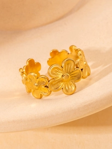 Detailed close-up of golden floral band ring with a matte finish on stone texture
