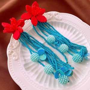 Detail of bohemian red felt flower earrings with dangling blue seed beads and sequins