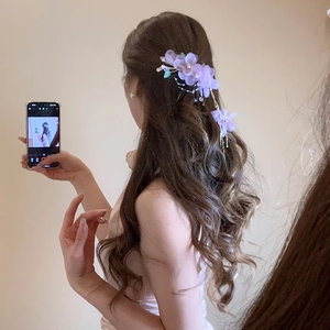 Détail d'une pince à cheveux fleurs en tissu lilas avec perles et longs glands pendants