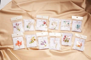 Assorted flower brooches with enamel finish and pearls on champagne satin background