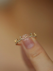 Macro shot of 18K gold plated crown ring with pavé-set zircons on woman's finger