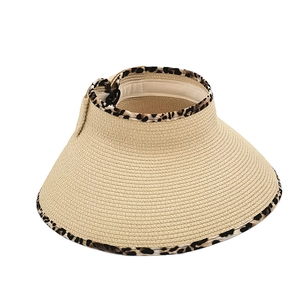 Detailed texture of straw sun visor with leopard print trim and woven bow detail