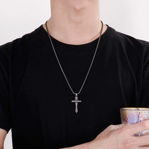 Gros plan d'un pendentif épée croix en acier inoxydable mat porté par un mannequin
