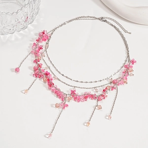 Detailed macro of layered necklace with pink resin flowers and beaded tassel fringe