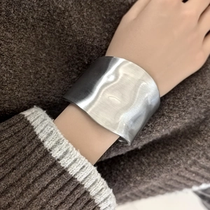 Close-up of minimalist silver wide cuff bracelet with irregular brushed metal texture