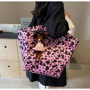 Detail of a pink cow print tote bag with a cute plush mouse charm for daily wear