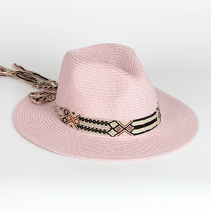 Detail of pink straw sun hat featuring ethnic geometric ribbon and woven tassel trim