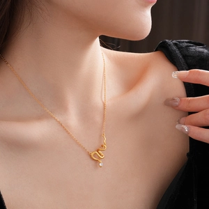 Close-up of a gold-plated snake pendant necklace with a clear zircon stone on model