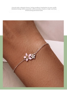 Macro view of pink enamel cherry blossom charms on a delicate S925 silver chain bracelet
