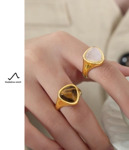 Detail of stainless steel rings with tiger eye and rose quartz in gold finish