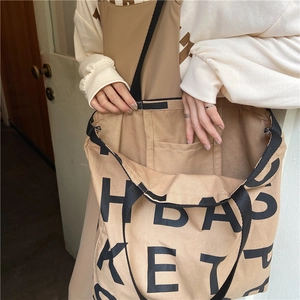 Detail of khaki canvas tote with interior pocket and black H BASKET lettering logo