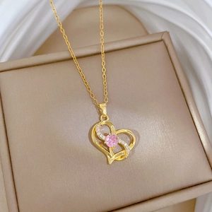 Irregular golden heart necklace with pink gemstone and crystals on jewelry box