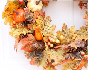 Close-up of autumn wreath featuring maple leaves, pine cones, and mini pumpkins on a white door
