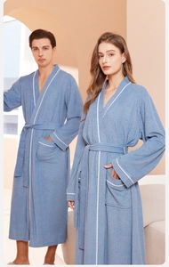 Detailed close-up of gray-blue couple bathrobe with white piping and terry cloth texture
