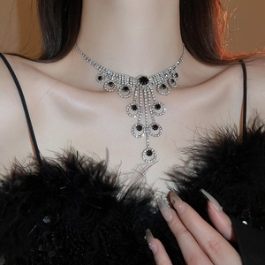 Macro view of silver luxury tassel necklace with black gem worn by a fashion model