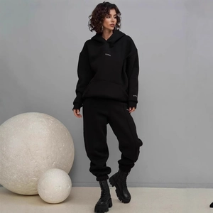 Detail of oversized black hooded tracksuit with minimalist logo and high-waist joggers