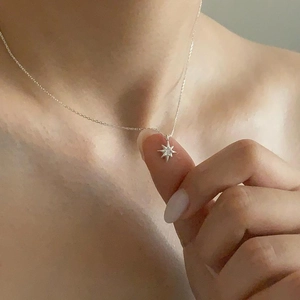 Close-up of 925 sterling silver starburst necklace with zircons on model neck