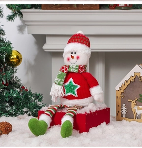 Détail d'un bonhomme de neige en peluche assis sur un coffret cadeau avec décor de Noël