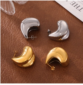 Detail of gold and silver teardrop earrings on a premium brown leather texture background
