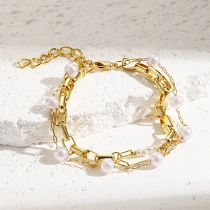 Detailed view of layered baroque pearl bracelet with gold chain on stone surface