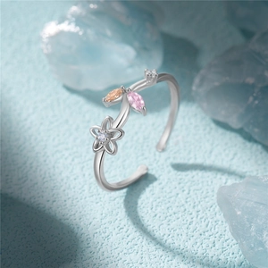 Macro detail of S925 silver flower ring featuring colorful zircons on a blue stone background