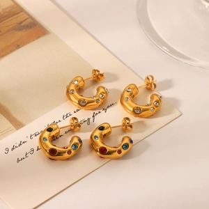 Close-up of gold-plated C-shaped stud earrings with clear and multicolor zircons