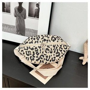 Detail of a beige leopard print woven waist bag with metallic zipper and strap