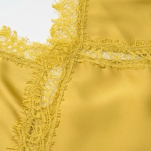 Macro shot of delicate yellow lace trim stitched on silky midi dress fabric