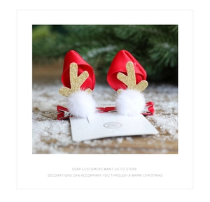 Detail of Christmas reindeer antler hair clips with white fur balls and red ribbon on snow