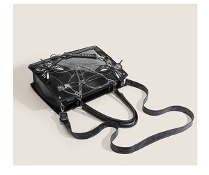 Close-up of black gothic ita bag featuring spiderweb patterns and butterfly chain accents
