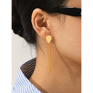 Macro side view of elegant golden drop earrings with long hanging metal tassels on model