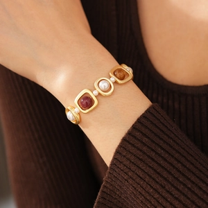 Gros plan du bracelet vintage doré avec perles et gemmes ambrées sur le poignet