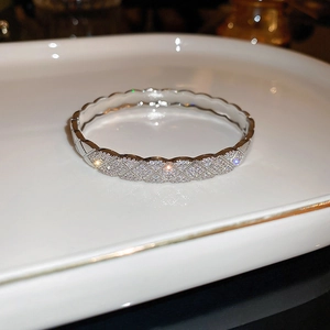 Macro detail of silver lattice bracelet with pavé-set zircons and scalloped edges