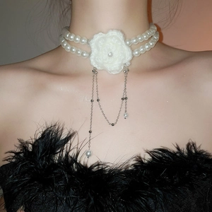 Gros plan d'un choker en perles rétro avec fleur au crochet et pompons argentés