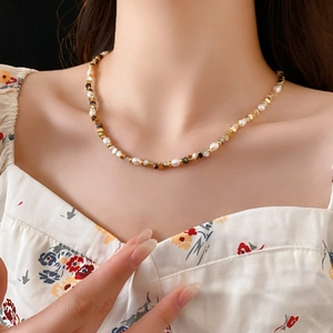 Detail of freshwater pearl necklace with gold beads on neck for minimalist style