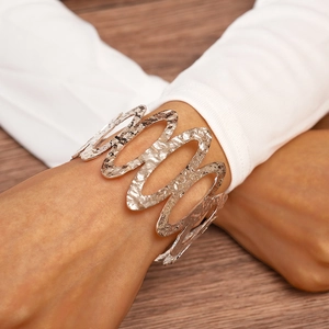 Close-up of a hollow wavy silver cuff bracelet with hammered texture on woman's wrist