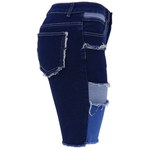 Detail of frayed raw hem and patchwork on dark blue denim shorts with fabric texture